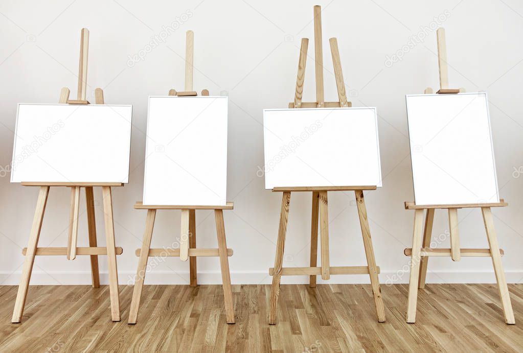 Four art studio easels with blank white painting frames
