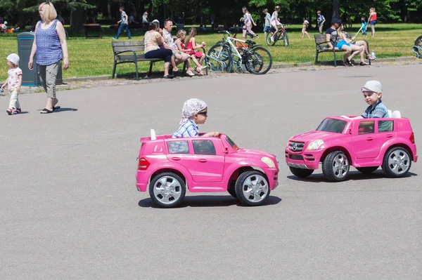 Dois meninos dirigindo carros elétricos de brinquedo em um parque — Fotografia de Stock