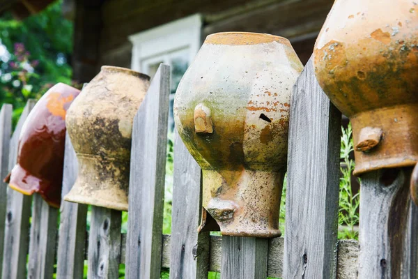 Viejas jarras de arcilla rota en valla de madera — Foto de Stock