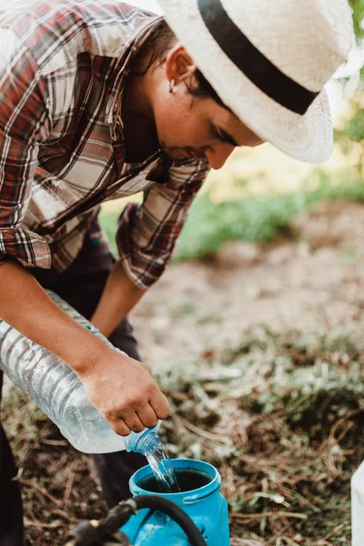 Young farmer preparing organic fertilizer with manual pump tank — 图库照片