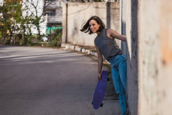Jeune femme avec skateboard bleu penny dans un port décontracté — Photo