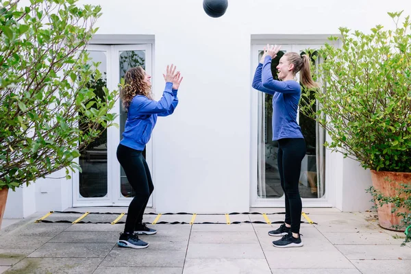 Две молодые женщины делают упражнения вместе с мячом для медицины — стоковое фото