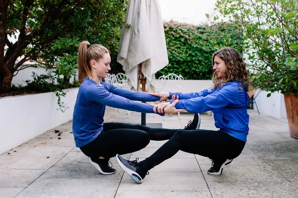 Two young women doing exercise together on a terrace — Stock Photo, Image