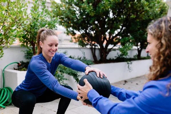 Two young women doing exercise together with medicine ball
