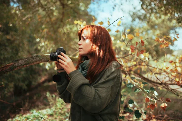 Mujer joven tomando fotos en el bosque con una vieja cámara — Foto de Stock