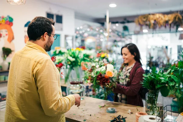 Mujer joven comprando un ramo de flores en una floristería — Foto de Stock