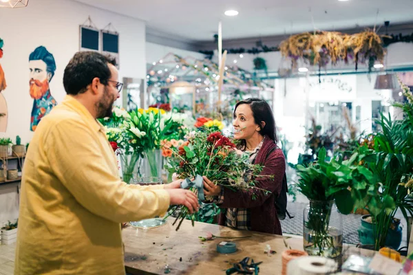 Νεαρή γυναίκα αγοράζει μπουκέτο λουλούδια σε ανθοπωλείο — Φωτογραφία Αρχείου