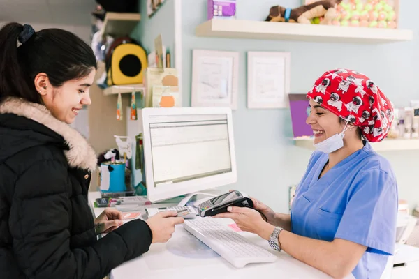 Jonge vrouw betaalt in een dierenarts met creditcard — Stockfoto