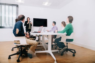 Bir grup ofis çalışanı patronun etrafında toplanıyor.