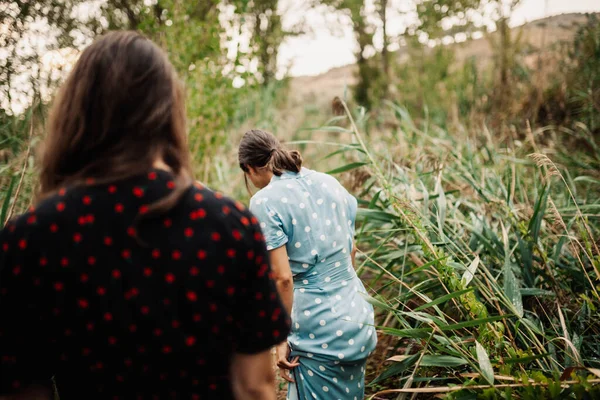 Visão traseira de duas jovens mulheres caminhando pelo campo — Fotografia de Stock