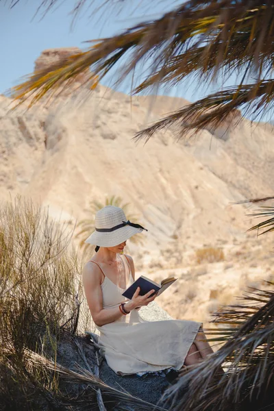 Mulher lendo um livro vestindo vestido assentos perto de palmeira — Fotografia de Stock