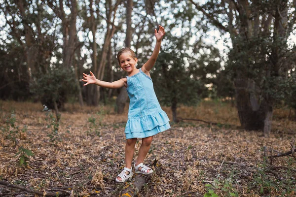 Ein Mädchen spielt schwungvoll über einen Baumstamm im Wald — Stockfoto