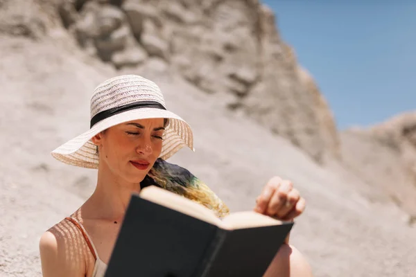 Woman reading a book wearing dress seating in the desert — Stock Photo, Image