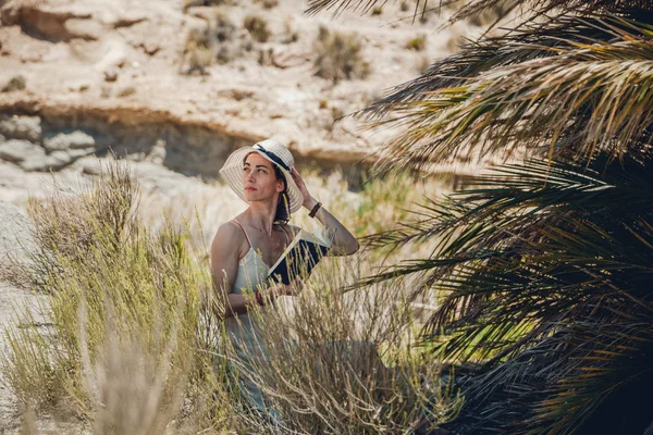 Femme lisant un livre portant une robe assise près du palmier — Photo