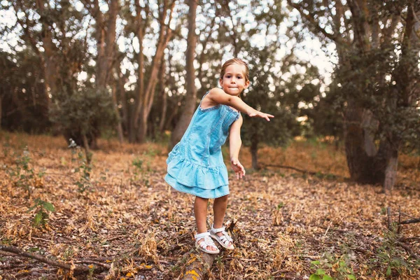 Děvče si hraje houpající se nad kmenem v lese — Stock fotografie