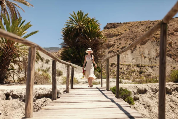 Mujer vestida caminando sobre un puente de madera en el desierto —  Fotos de Stock