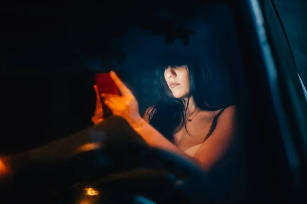 Jovem mulher dentro de um carro usando seu smartphone — Fotografia de Stock