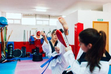 İki genç kadın bir eğitim merkezinde tekvando çalışıyor.