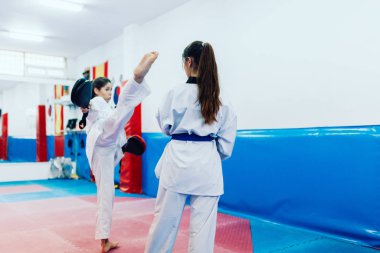 İki genç kadın bir eğitim merkezinde tekvando çalışıyor.