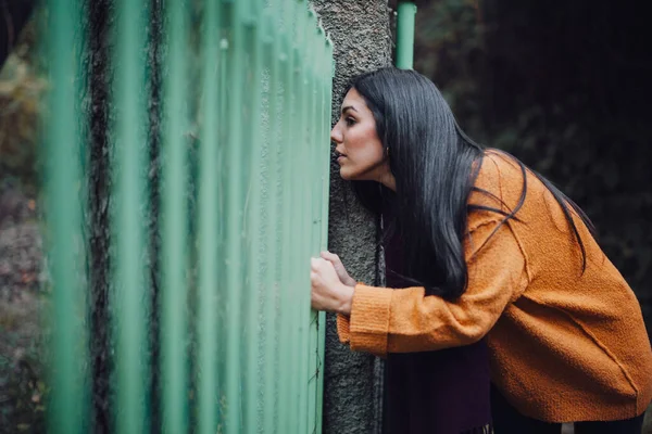 Жінка дивиться через металевий паркан в лісі — стокове фото