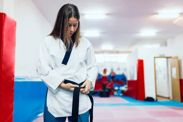 Young woman dresses in her taekwondo suit in front of the mirror — Stock Photo, Image