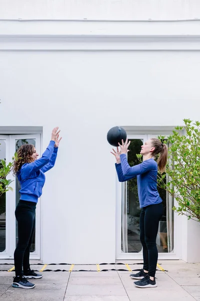 Две молодые женщины делают упражнения вместе с мячом для медицины — стоковое фото