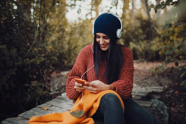 Jeune femme écoutant de la musique avec son casque dans la forêt — Photo