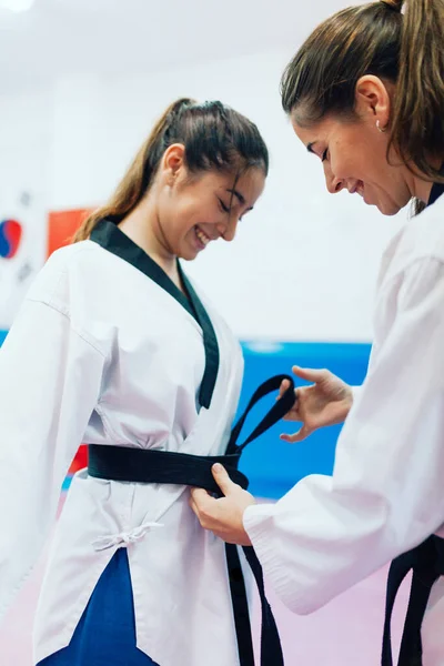 Two young women dress each other in their taekwondo suit — Stock Photo, Image