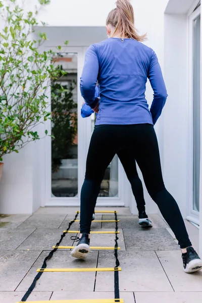 Two young women doing agility ladder exercise on a terrace