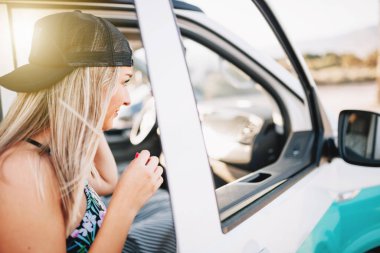 Genç bir kadın sahildeki minibüsün aynasında kendine bakıyor.