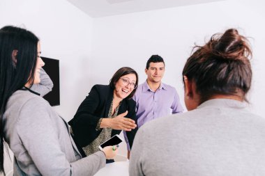 Bir grup ofis çalışanı patronun etrafında toplanıyor.