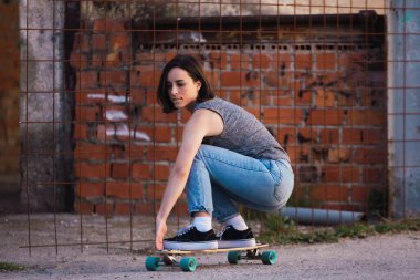 Young skater woman riding on her longboard in the village in casual wearing, freedom concept