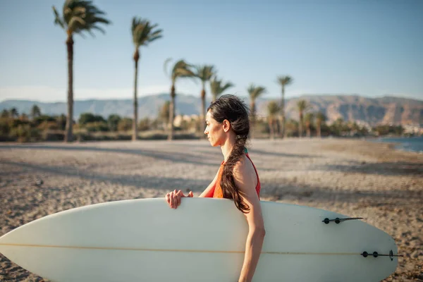 Genç Bir Kadın Sörf Tahtasıyla Sahilde Yürüyor — Stok fotoğraf