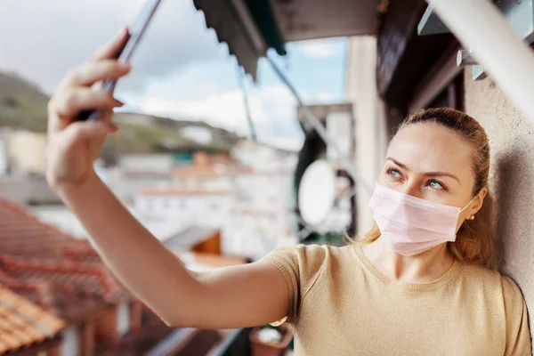 Kadın, karantina sırasında cerrahi maske takarak selfie çekiyor.