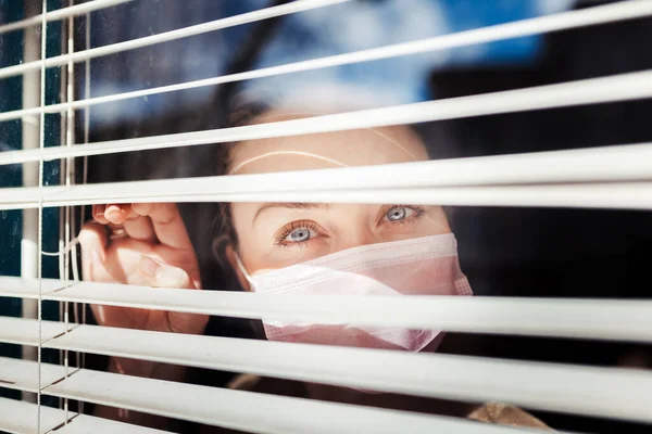 Frau Blickt Mit Maske Aus Dem Fenster — Stockfoto