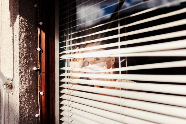 Woman Looking Out Blind Window Wearing Surgical Mask — Stock Photo, Image