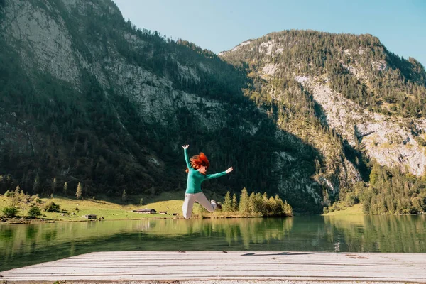 Genç Bir Kadın Dağların Altındaki Bir Gölün Yakınındaki Iskelede Atlıyor — Stok fotoğraf