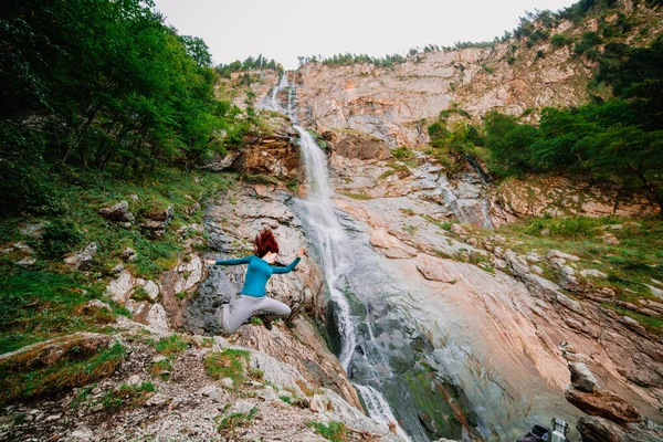 Молодая Женщина Прыгает Гору Возле Водопада — стоковое фото