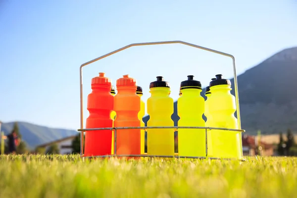 Uppsättning av vattenflaskor på fotboll fältet bakgrund — Stockfoto