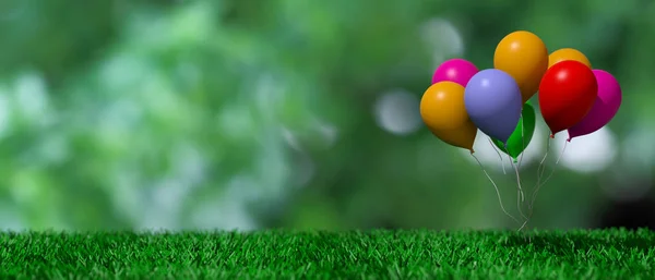 Grupp av färgglada ballonger på grönt gräs och abstrakt bakgrund. 3D illustration — Stockfoto