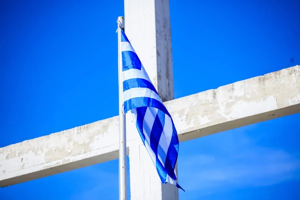 Greek flag on a white cross and blue sky background — Stock Photo, Image