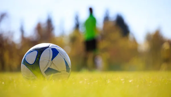 Soccer ball in field on the left side ready to be kicked. Blurred player and nature background. — Stock Photo, Image