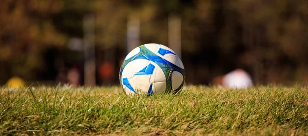 Bola de futebol no meio de um campo pronto para ser chutado. fundo natureza desfocada . — Fotografia de Stock