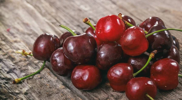 Un montón de cerezas rojas, sobre una superficie de madera . — Foto de Stock