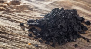 Ahşap masa üzerinde siyah tuz yığını. Closeup görünümü.