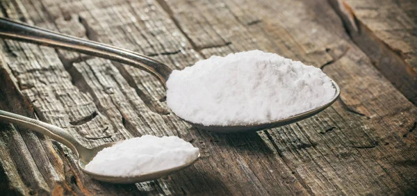 Tablespoon and teaspoon with baking soda, on wooden background. Close up view. — Stock Photo, Image