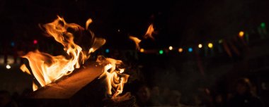 Alevler ve bokeh ışıkları ile ateş. Gece arka plan bulanık kişilerle şenlik ateşi. Yakın, Ayrıntılar, afiş, metin için boşluk.
