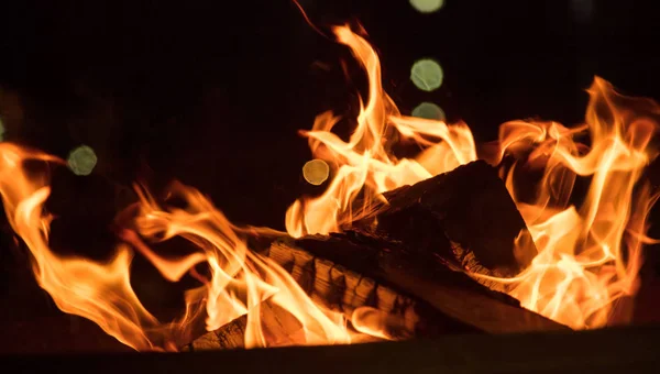 Feuer im Kamin mit bunten Flammen auf schwarzem Hintergrund. Nahaufnahme mit Details, Raum. — Stockfoto