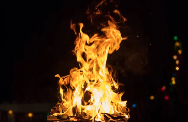 Fuego con llamas y luces bokeh. Gran resplandor sobre fondo negro borroso. Vista cercana con detalles, espacio para texto . —  Fotos de Stock