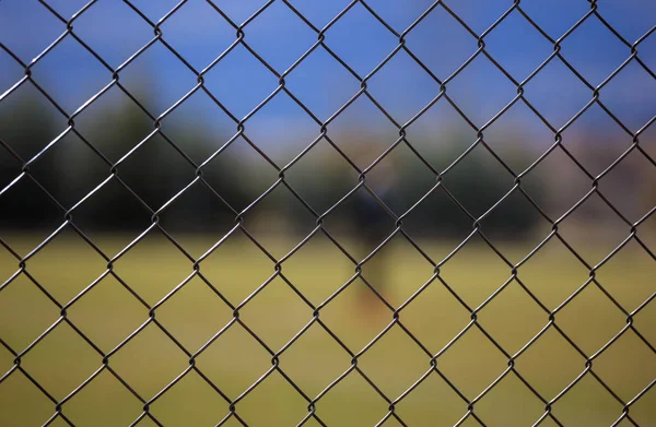 Draad metalen gaas hek rond een voetbalveld. Onscherpe achtergrond, close-up weergave met details. — Stockfoto